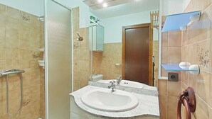 Une salle de bain avec une douche à parois de verre, un lavabo blanc et un miroir au-dessus.