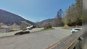 Une route de montagne avec des véhicules, un bâtiment et un ciel dégagé.