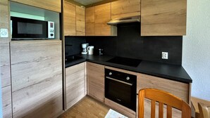 A compact kitchen with wooden cabinets, a microwave, a coffee maker, and a dishwasher.