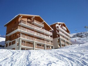 Um hotel de vários andares com varandas e um teleférico ao fundo.