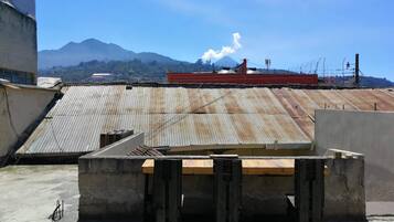 A rooftop with a corrugated metal roof, concrete walls, and a wooden platform.