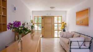Zona de recepción con mostrador de madera, un sofá y una puerta que da al exterior.
