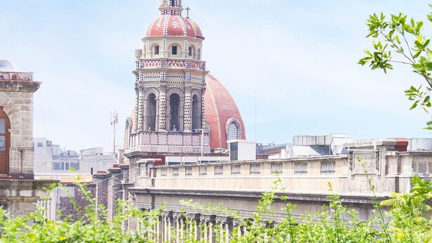 A rooftop terrace with a view of a historic building with a red dome and bell tower. - MyPlace Zócalo (Mexico City)