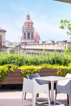 A rooftop terrace with a view of a historic building with a red dome and bell tower. - MyPlace Zócalo (Mexico City)