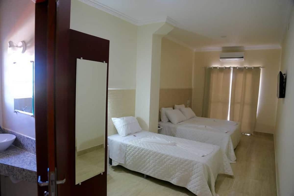 Une chambre d’hôtel avec deux lits, une salle de bain avec un lavabo et un appareil de climatisation.