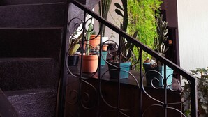 A staircase with black steps and metal railings, flanked by potted plants and framed artwork on the walls. - Lar Antiqua Hotel (Quetzaltenango)