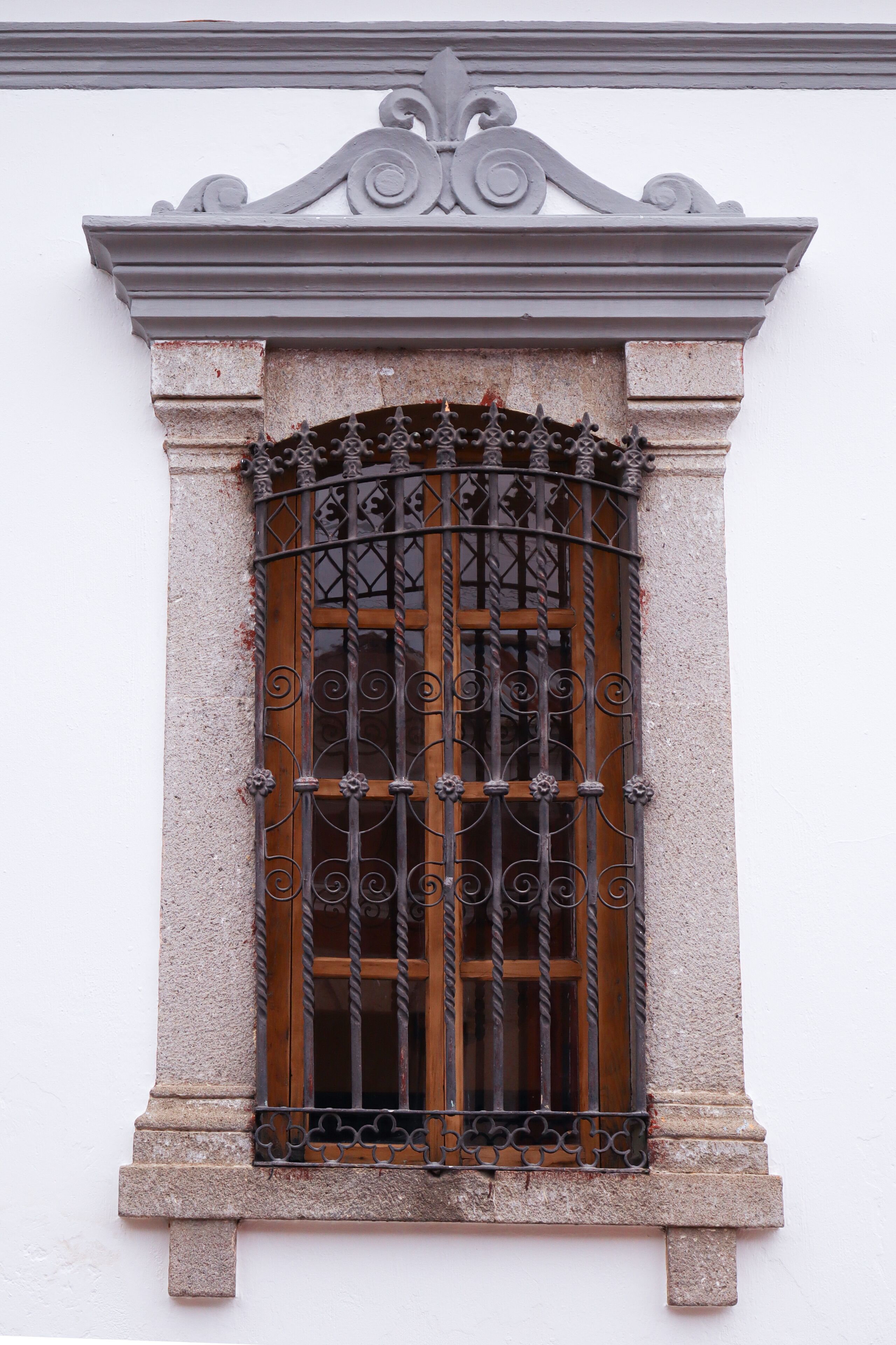 A window with ornate metal bars and a stone frame.