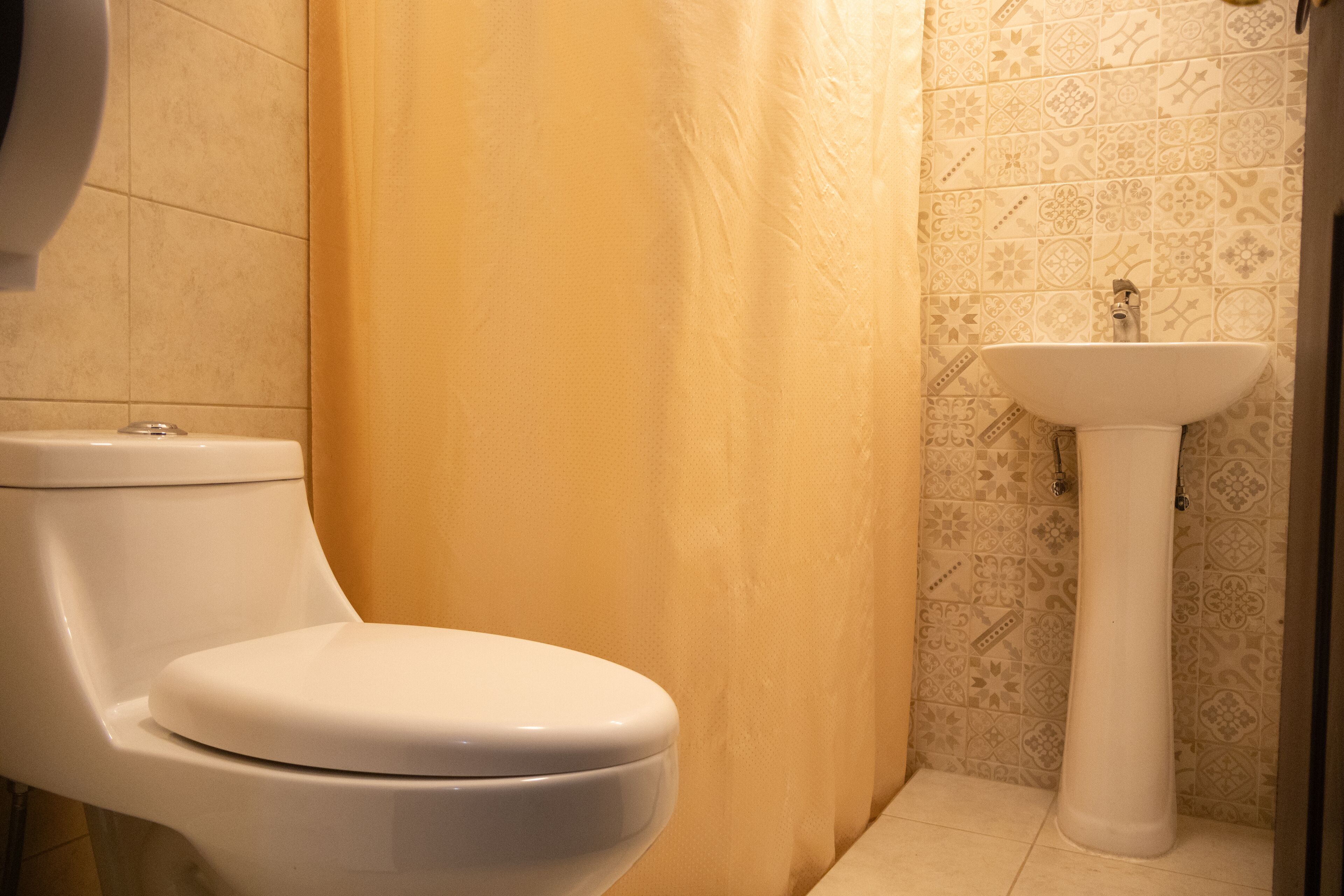 A bathroom with a toilet, a sink, and patterned tiles.