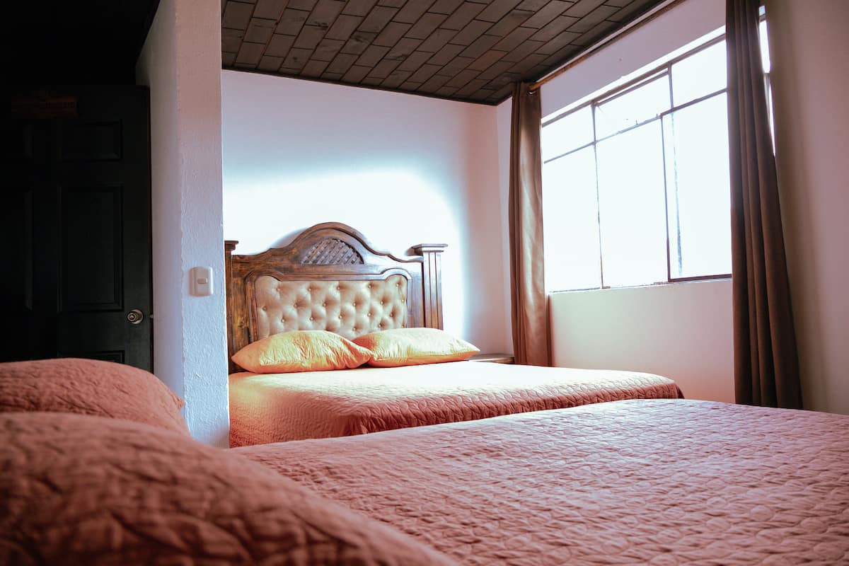 Un dormitorio con una cama grande, cabecera de madera y una ventana con cortinas.