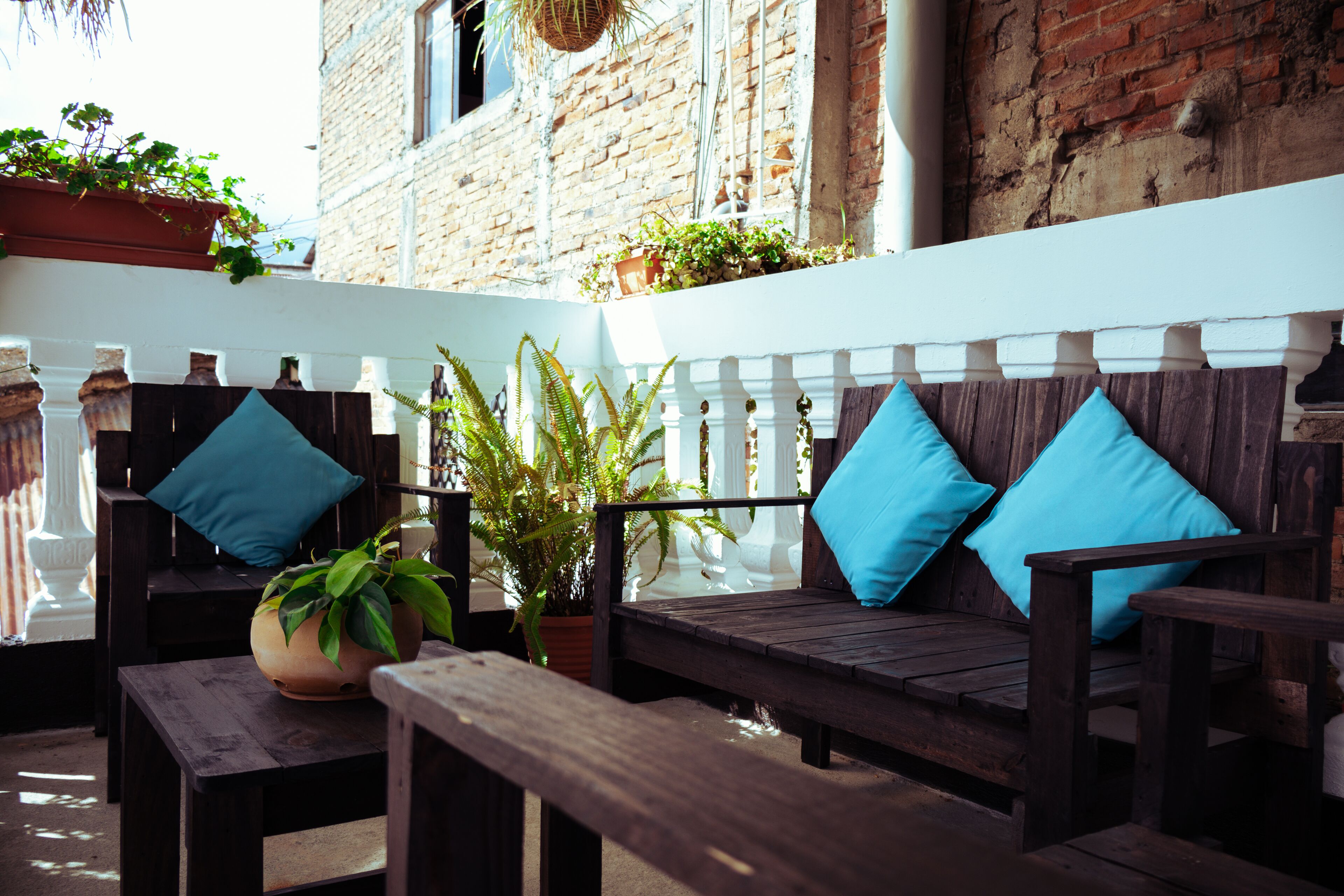 A wooden bench with blue cushions and a potted plant.