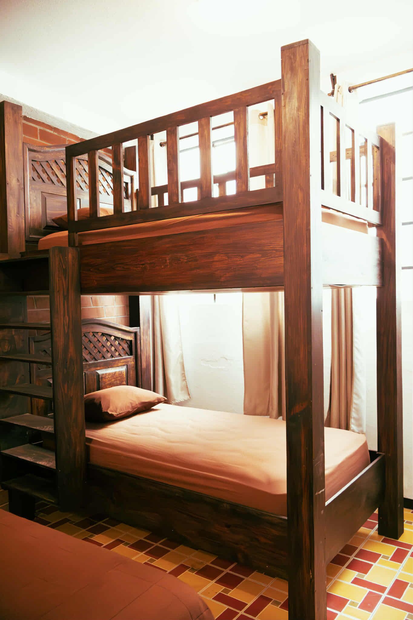 Un lit superposé avec une structure en bois et un matelas, une échelle en bois et une petite étagère avec un oreiller.