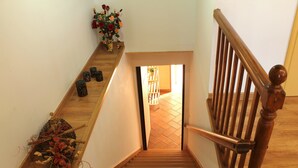 Una escalera de madera con barandilla que conduce a una habitación con piso de baldosas.