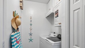 A laundry room with a washing machine, a drying rack, and a wall-mounted star decoration.