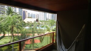 A balcony with a hammock, a view of a sports court, and a building in the background. - Riviera apartment, 50m from the beach 3 bedrooms 2bh, living room 2 rooms, balcony, air conditioning, wi-fi  (Bertioga)