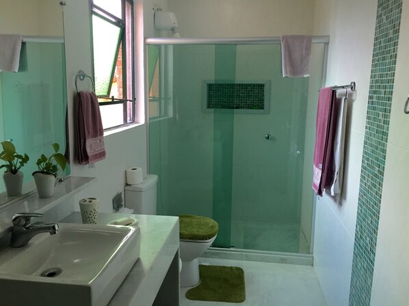 A bathroom with a sink, mirror, toilet, and shower area.