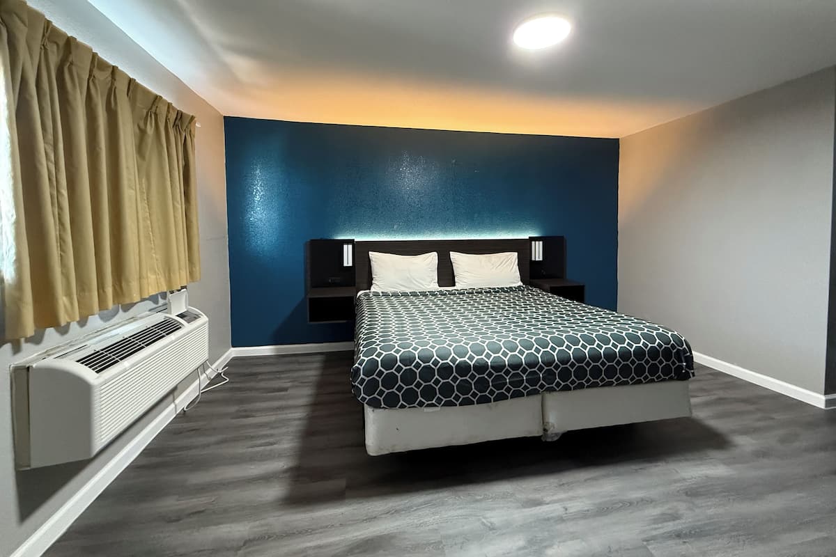 Une chambre à coucher avec un lit, une table de chevet, un radiateur et une fenêtre avec des rideaux.