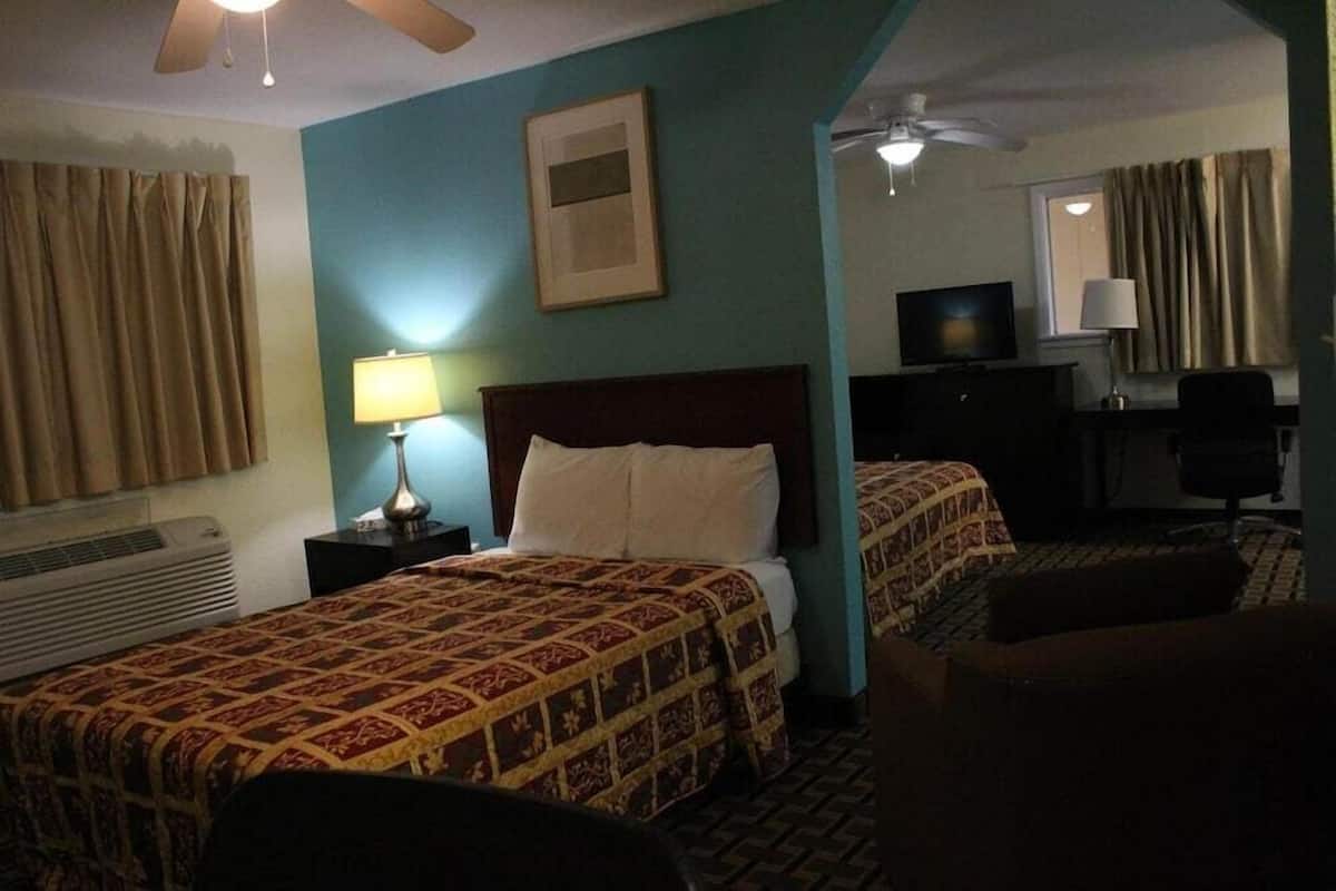 Une chambre d’hôtel équipée d’un lit, d’un bureau, d’une chaise, d’une télévision et d’un ventilateur de plafond.