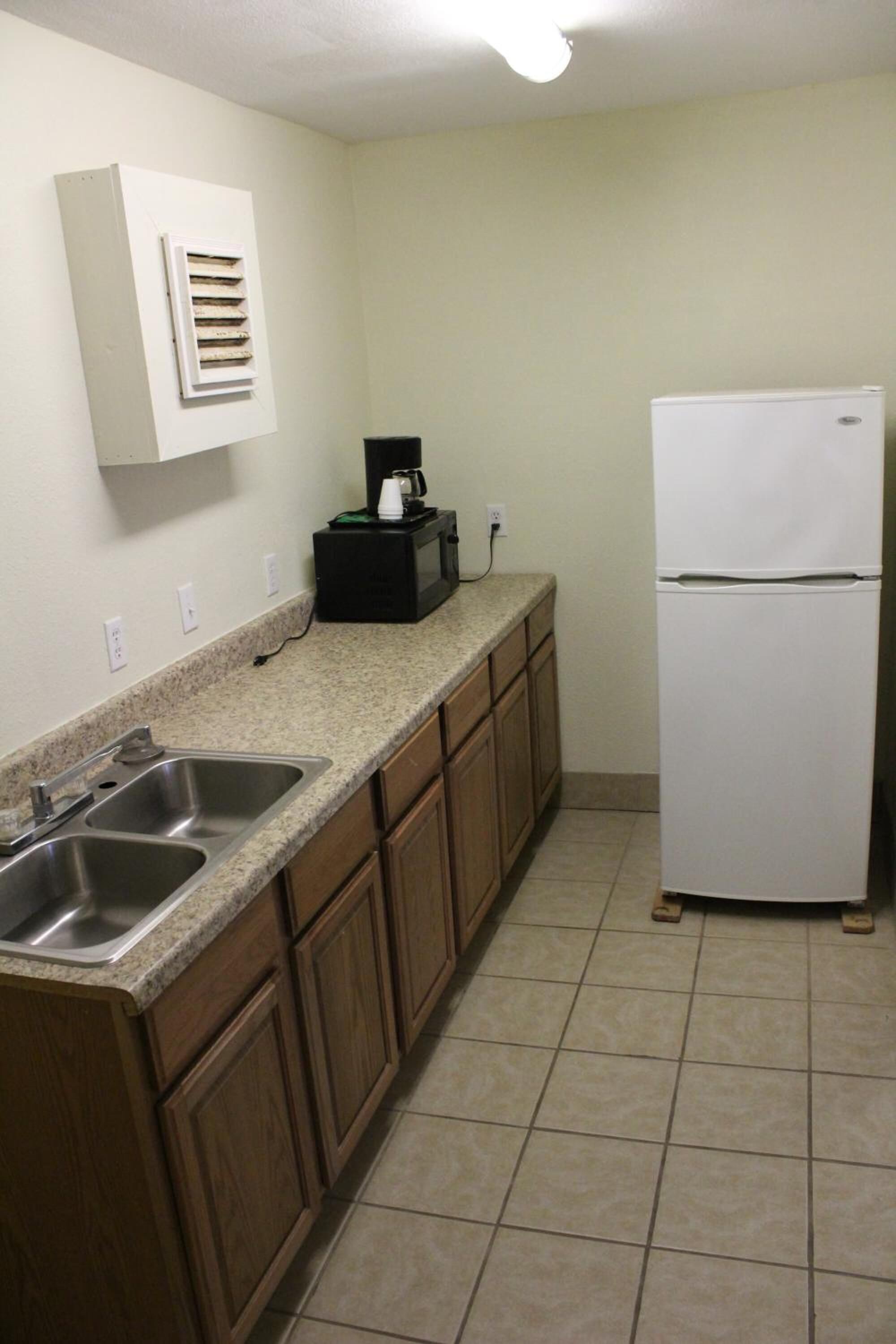 A kitchen with a double sink, a white refrigerator, and a microwave on the countertop.