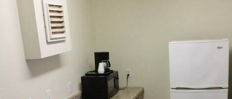 A kitchen with a double sink, a white refrigerator, and a microwave on the countertop.