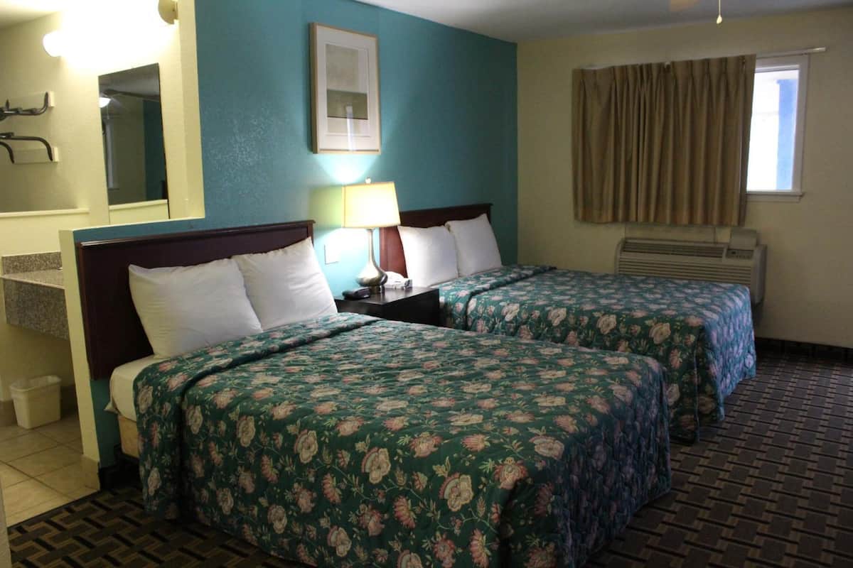 Une chambre d’hôtel avec deux lits, une salle de bain, une fenêtre avec des rideaux et un climatiseur fixé au mur.