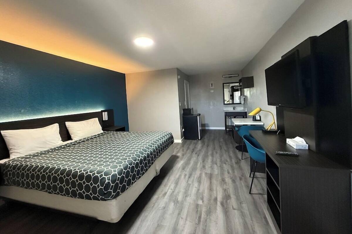 Une chambre d’hôtel équipée d’un lit, d’un bureau, d’une chaise, d’une télévision et d’une petite kitchenette.