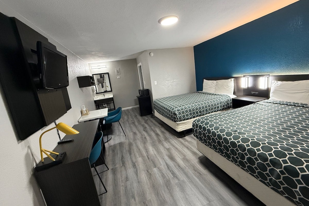 Une chambre d’hôtel de taille réduite, comprenant un lit, un bureau, une chaise, une télévision et une petite salle de bain.