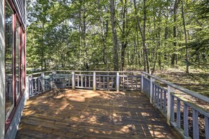 Enjoy outdoor dining or relaxation on this serene deck surrounded by a dense forest.