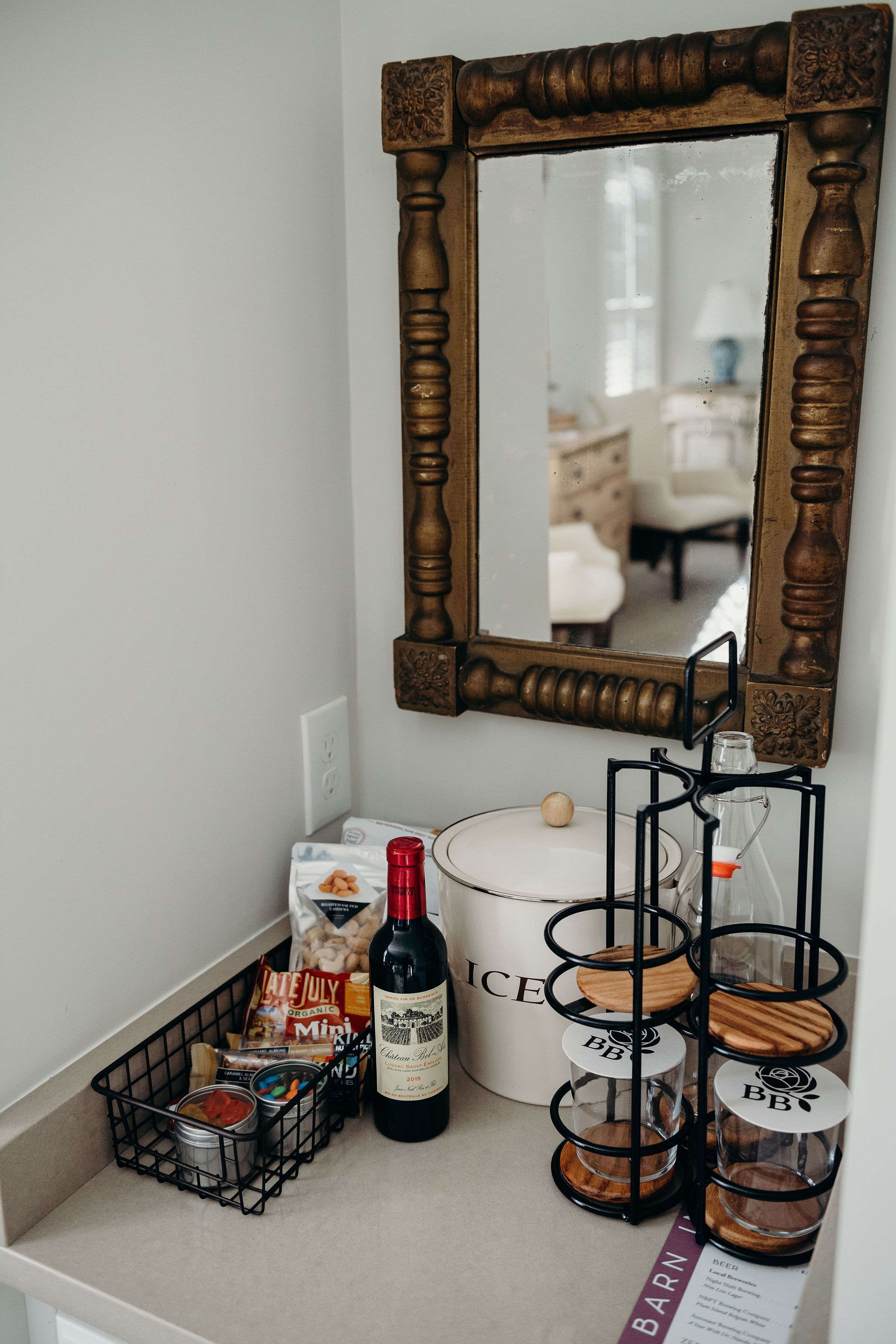 A kitchen counter with a wine bottle, a coffee maker, a basket of snacks, and a milk jug.