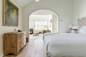 A bedroom with a large bed, a wooden dresser, a desk with a chair, and a painting on the wall. - Briar Barn Inn (Rowley)