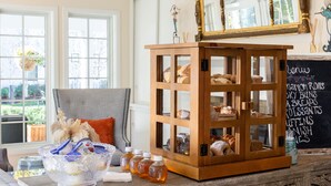 Un gabinete de madera con intrincados grabados, un cuenco de vidrio con adornos y un menú en una pizarra que enumera productos de panadería.