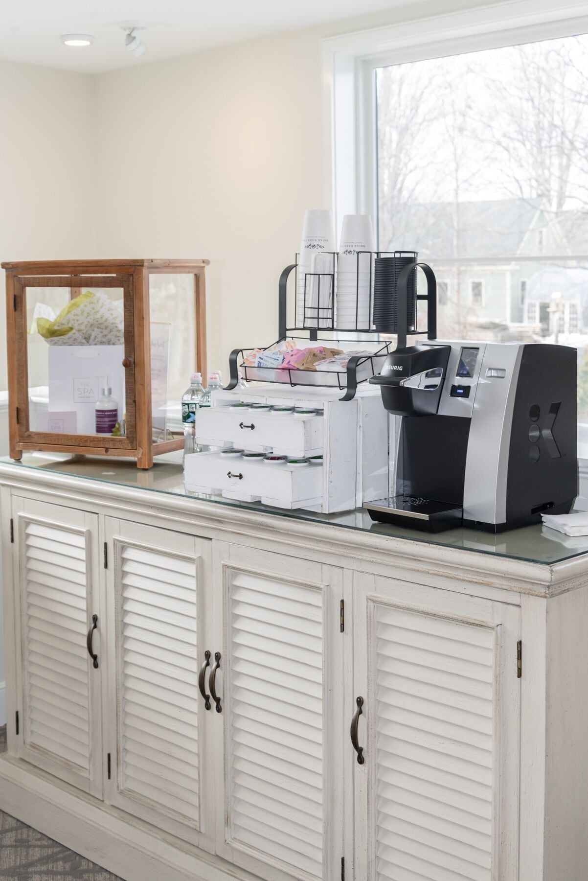 A kitchenette with a coffee maker, a small refrigerator, and a cabinet with drawers.