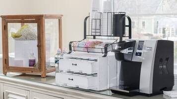 A kitchenette with a coffee maker, a small refrigerator, and a cabinet with drawers.