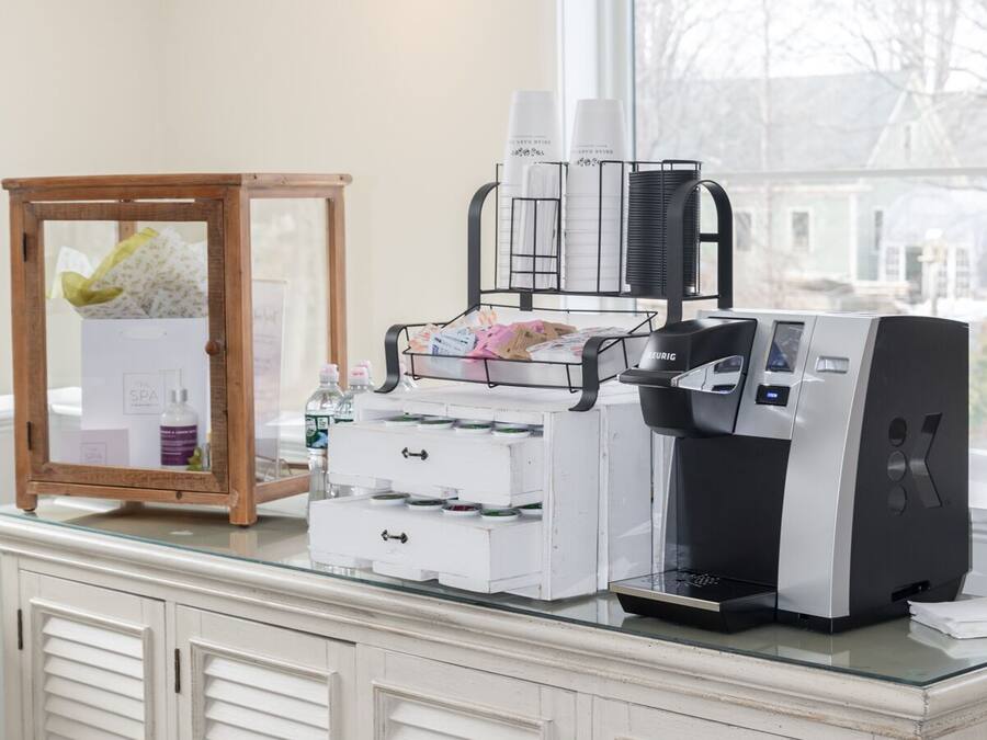 A kitchenette with a coffee maker, a small refrigerator, and a cabinet with drawers.