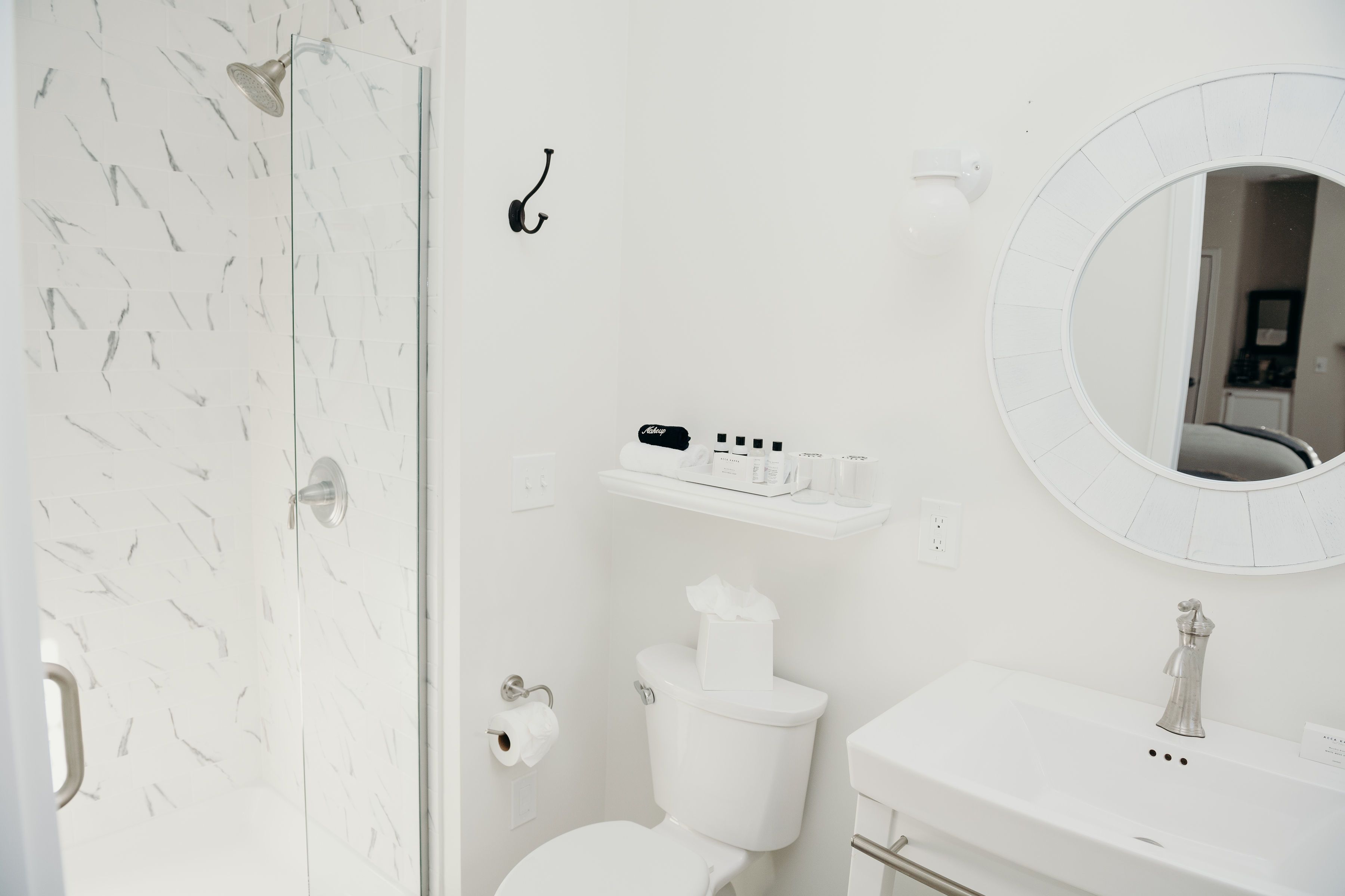 A bathroom with a toilet, a sink, a mirror, and a shower.