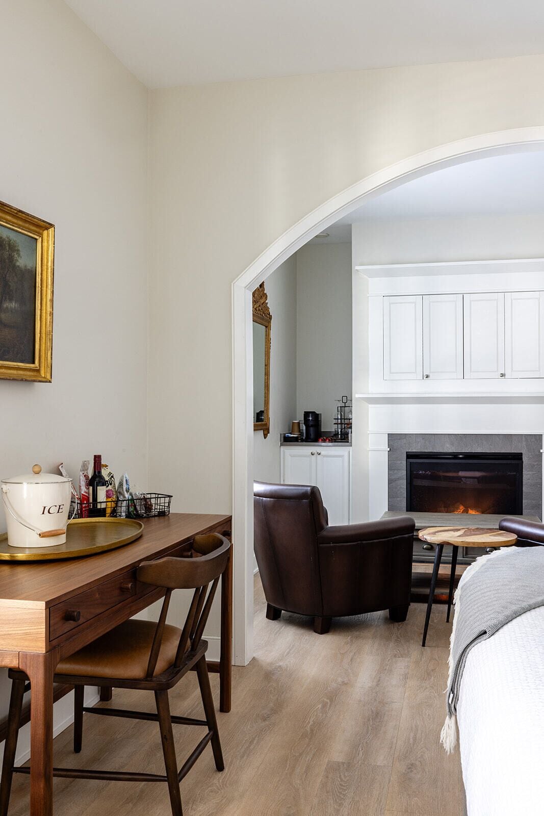 Une pièce comprenant une table à manger, des chaises, un buffet blanc, une cheminée et un tableau au mur.