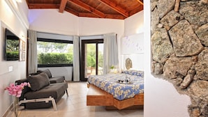 A bedroom with a bed, a sofa, and a stone wall.