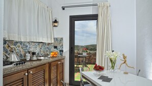 A kitchen with a tiled backsplash, a stove, and a dining area with a table and chairs.