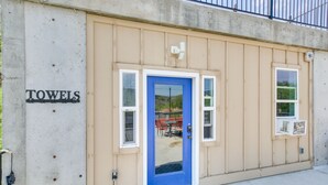 Un edificio con una porta blu, un cartello con la scritta 'TOWELS' e una finestra con un condizionatore d'aria.