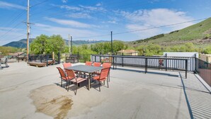 Patio esterno con tavolo e sedie, circondato da una recinzione in metallo, con vista su un paesaggio collinare.