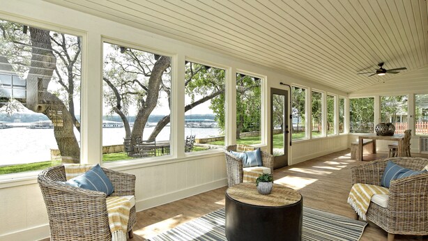 A covered patio with wicker furniture, a round coffee table, and large windows overlooking a river. - LOCATION!!  Lake Travis Waterfront~Pool, Spa, Outdoor Kitchen, Location (Austin)