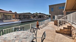 Un patio frente al agua con una mesa y sillas, un canal y edificios al fondo.