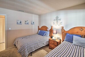 Een slaapkamer met twee bedden, gestreept beddengoed, een nachtkastje met een lamp en wanddecoratie.