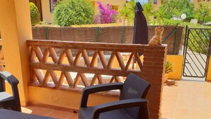 An outdoor patio area with wicker furniture, a wooden fence, and a view of neighboring buildings. - House (triplex) in Puerto Rey, Vera Playa, Almeria, 400m from beach (Puerto Rey, Vera Playa)