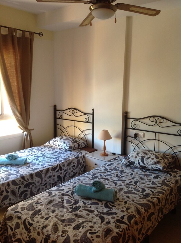 A bedroom with two single beds, a ceiling fan, and a window with curtains. - House (triplex) in Puerto Rey, Vera Playa, Almeria, 400m from beach (Puerto Rey, Vera Playa)