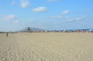 A sandy beach with a lifeguard tower, umbrellas, and people.