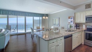 Una cocina moderna con una isla grande, un comedor con vista al océano y una amplia sala de estar con balcón.