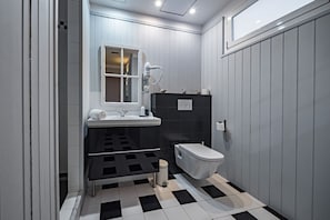 A modern bathroom with a black and white checkered floor, a white sink, a black vanity, and a toilet.