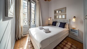 Ein Schlafzimmer mit einem großen Bett, zwei Nachttischen, einem Schminktisch und einem Fenster mit Vorhängen.