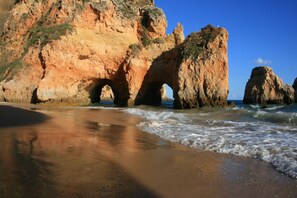 A beach with natural rock formations and waves. - Charming villa, beautiful sea view. Swimming pools. Sand beach. Very calm. (Porches)