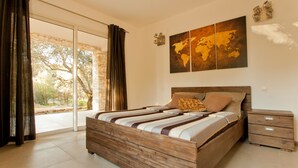 Camera da letto con un letto grande, una testata in legno, un comodino e vista all'esterno attraverso una porta in vetro.